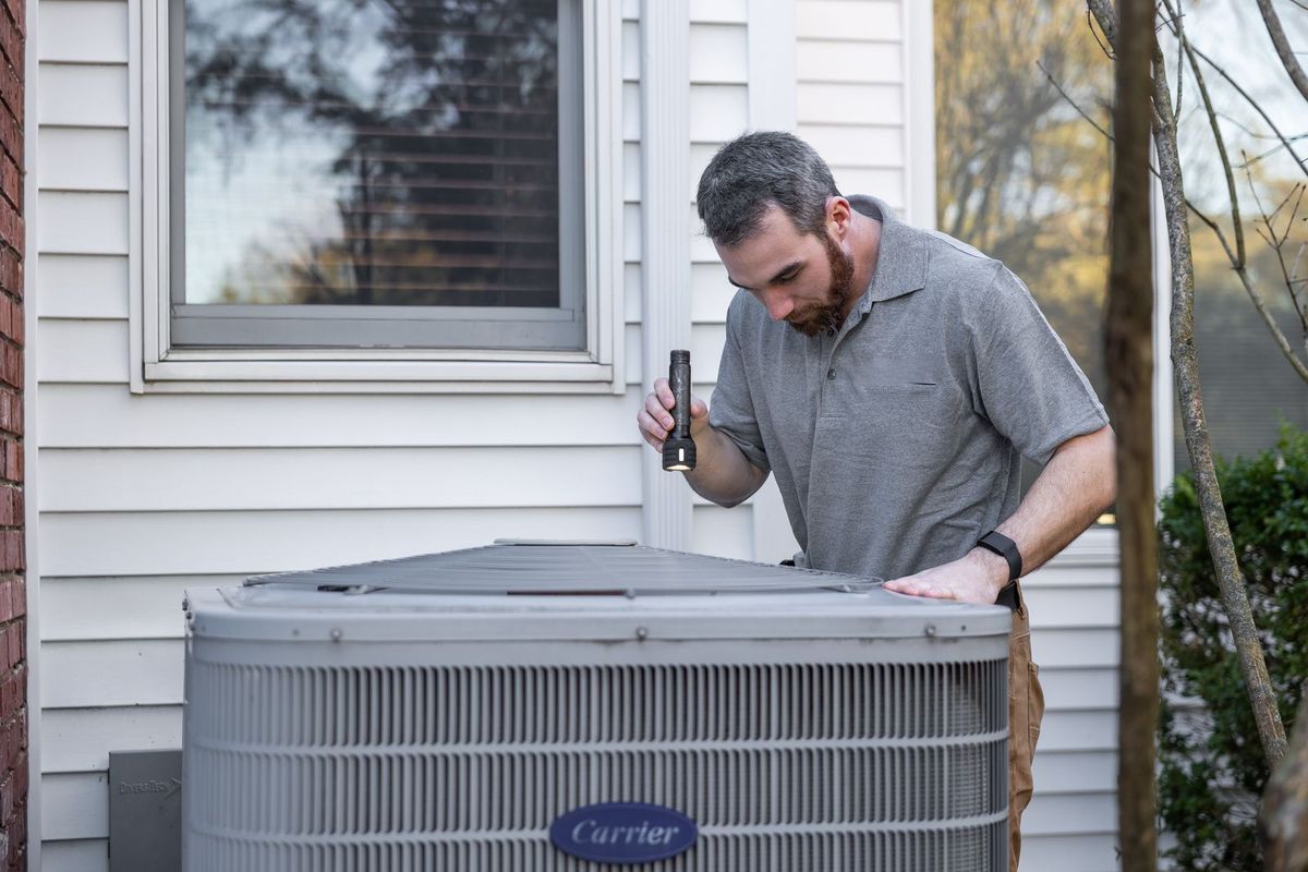 Technician inspecting an HVAC unit at a home
