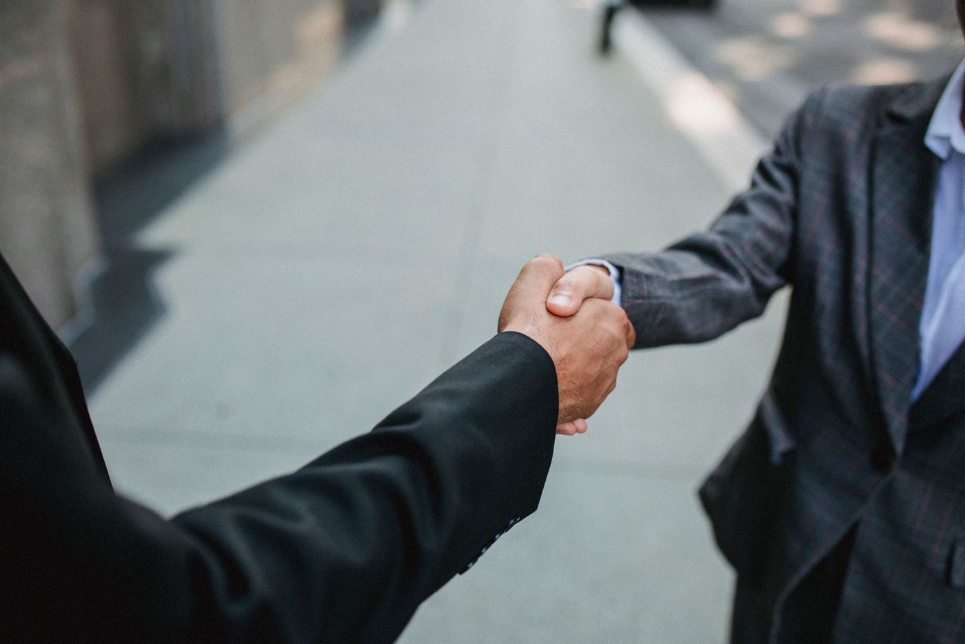 Two businessmen shaking hands on a city street